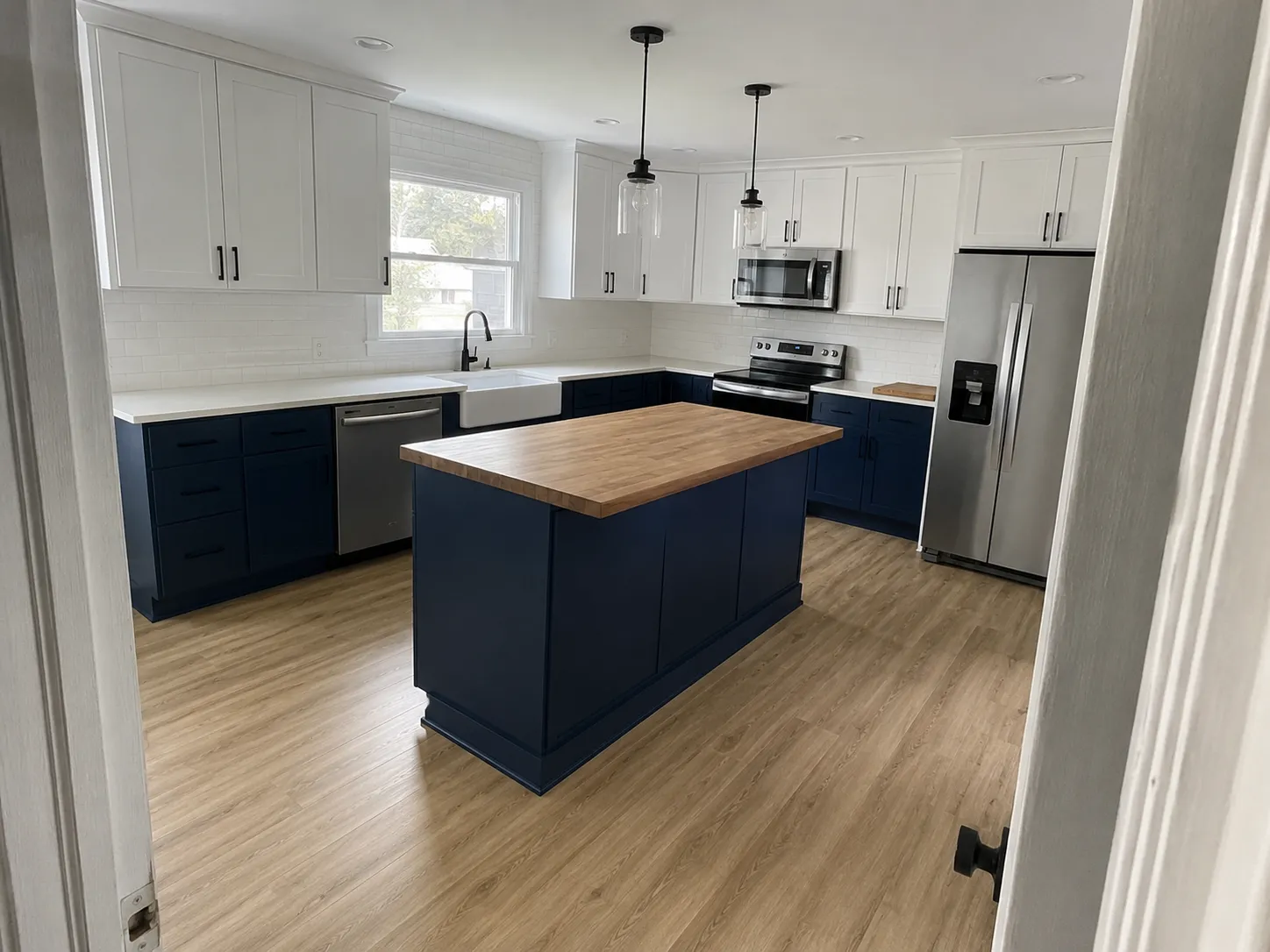 Kitchen remodel in Topeka, KS with navy and white shaker cabinets and a butcher block island