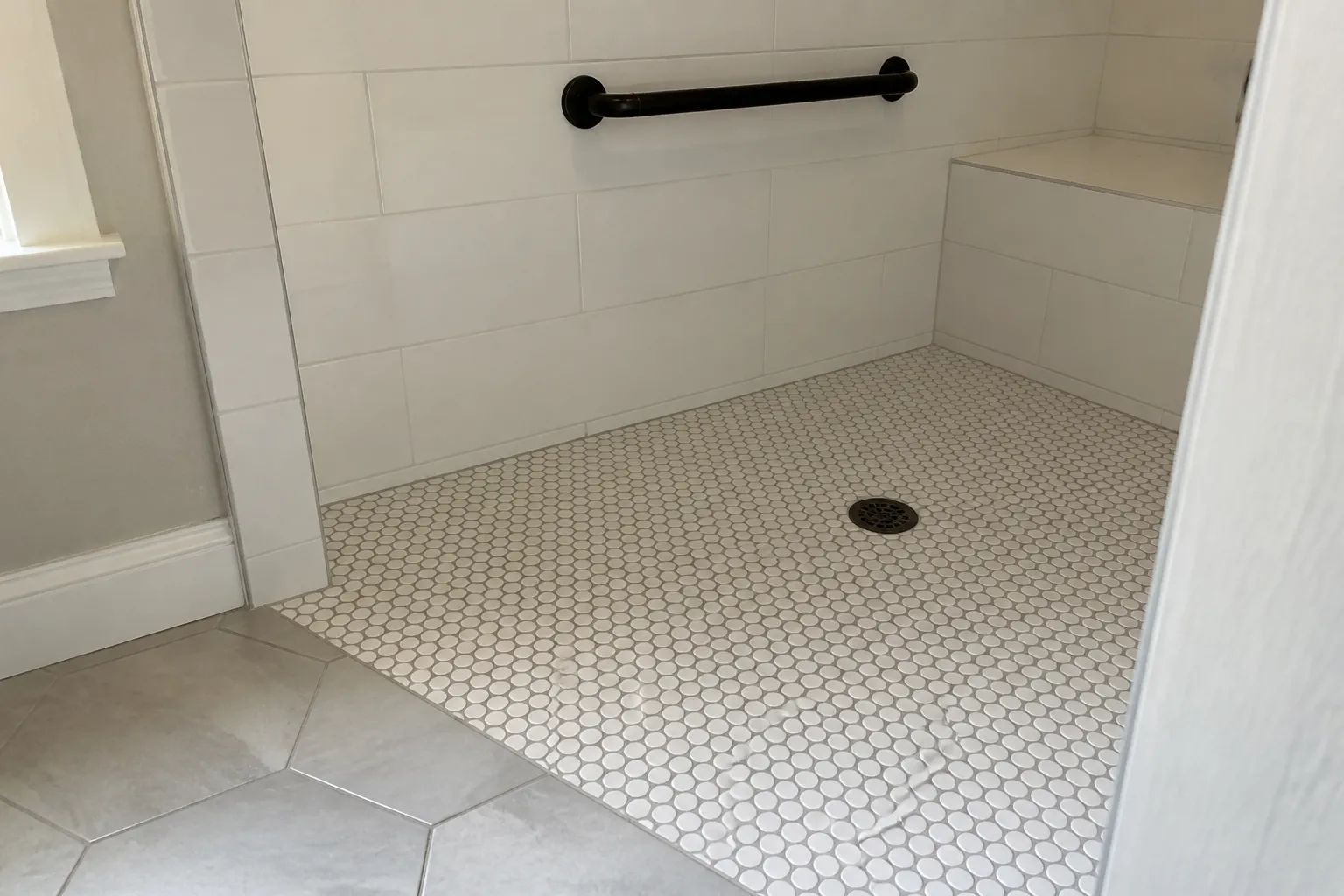 Mosaic tile shower pan and drain detail, typical of a tiled bathroom remodel in Topeka, KS